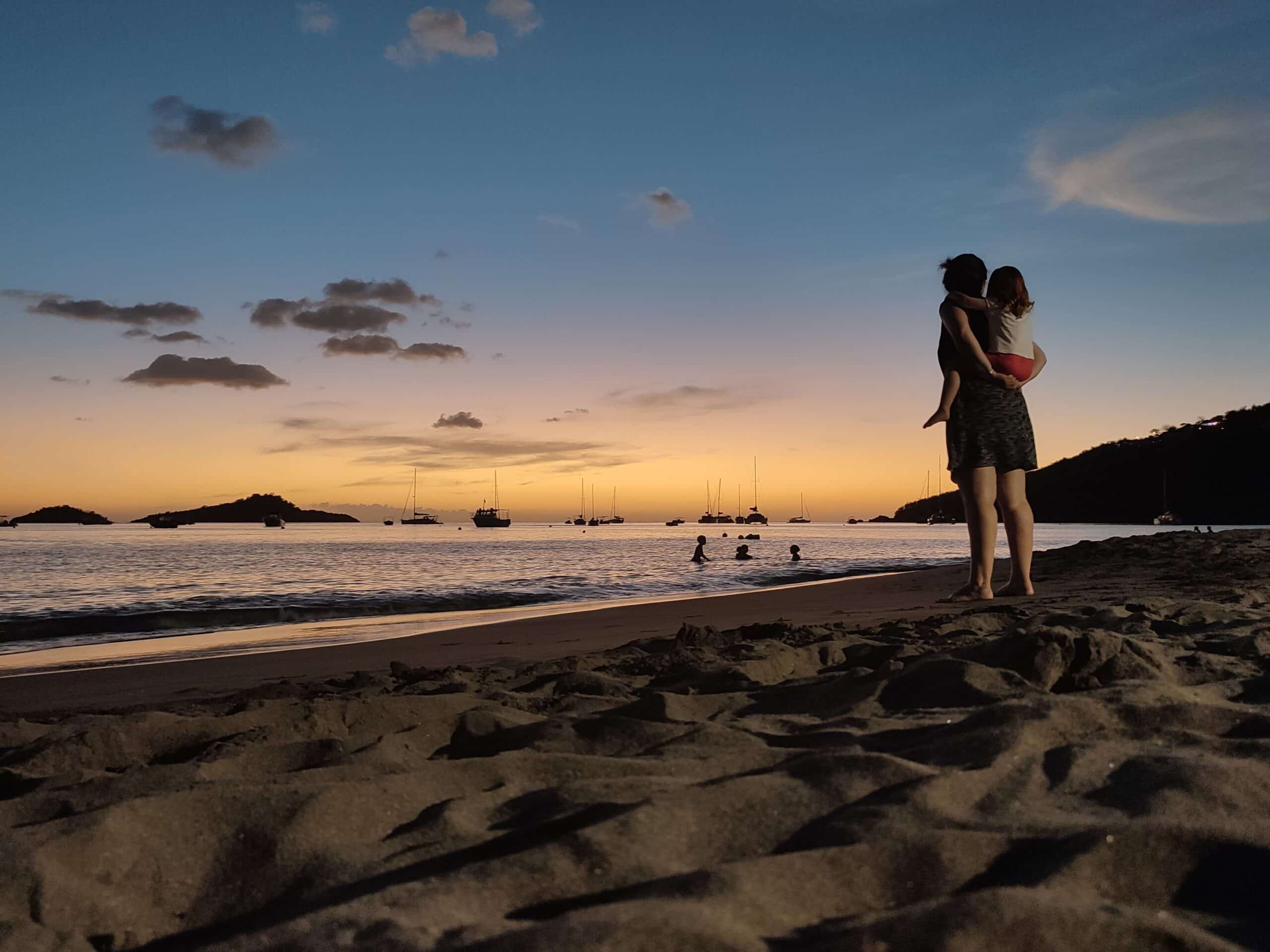 maman et sa fille qui regarde un coucher de soleil sur la plage